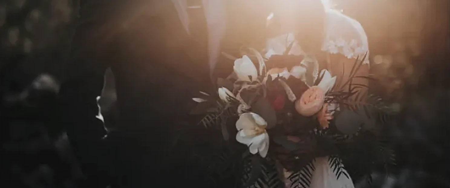 Cena de um filme de casamento: os noivos com o buquê, em luz de fim de tarde.